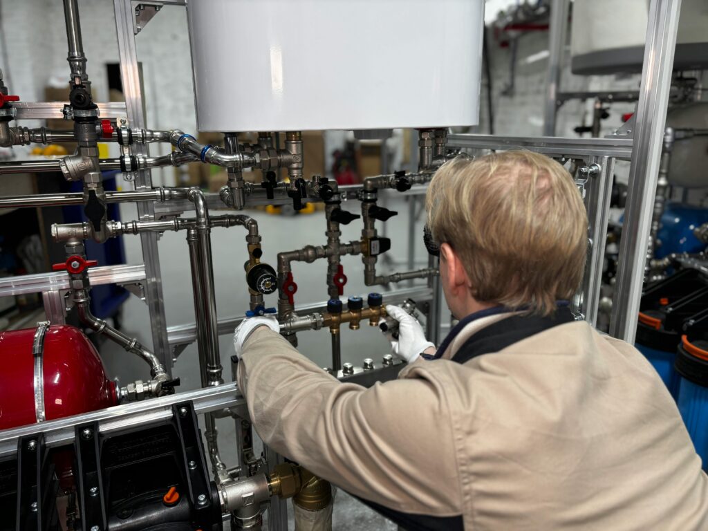 Engineer working on industrial pipe system in a factory for heating and production adjustment.